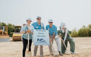 Family in front of welcome home sign digging into the dirt prior to beginning building.